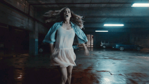 A Woman In A White Dress Is In A Parking Garage GIF