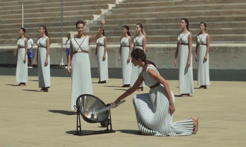 a woman in a white dress is kneeling in front of a group of women in white dresses