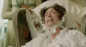 A Woman In A White Dress Is Laying In A Hospital Bed And Crying . GIF