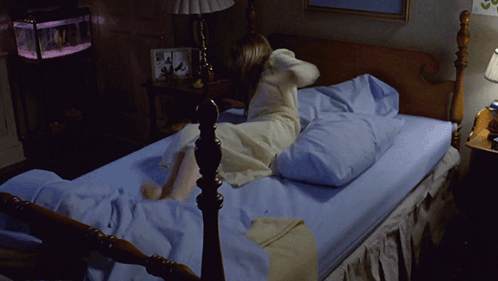 A Woman In A White Dress Is Laying On A Bed GIF