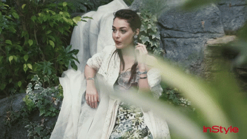 A Woman In A White Dress Is Laying On A Rock With Instyle Written On The Bottom Left GIF