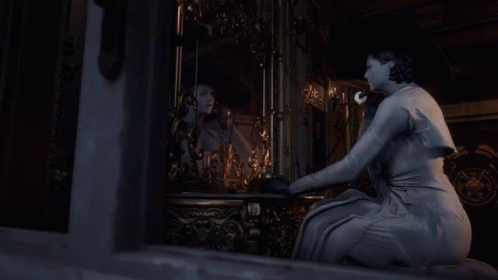 A Woman In A White Dress Is Looking At Herself In A Mirror GIF