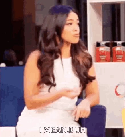A Woman In A White Dress Is Sitting In A Chair And Talking To Someone . GIF