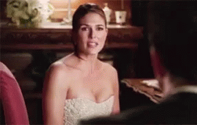 A Woman In A White Dress Is Sitting Next To A Man In A Suit . GIF