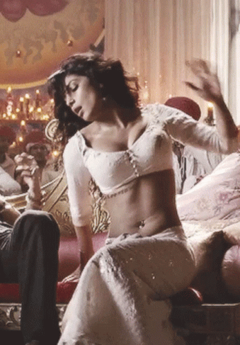 A Woman In A White Dress Is Sitting On A Couch GIF