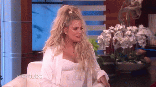 A Woman In A White Dress Is Sitting On A Couch On A Television Show . GIF