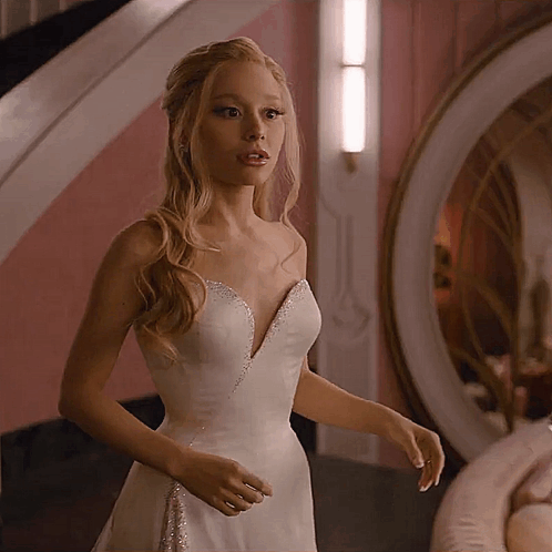 A Woman In A White Dress Is Standing In A Room GIF