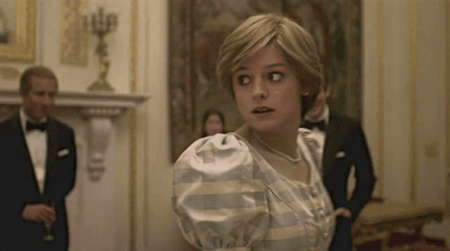 A Woman In A White Dress Is Standing In A Room With A Man In A Tuxedo . GIF