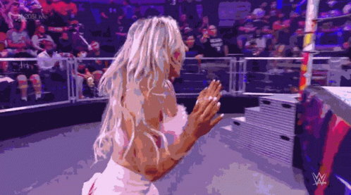 A Woman In A White Dress Is Standing In A Wrestling Ring GIF