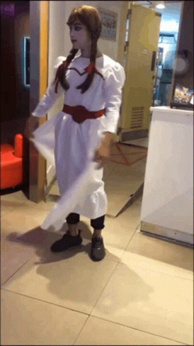 A Woman In A White Dress Is Standing In Front Of A Counter GIF