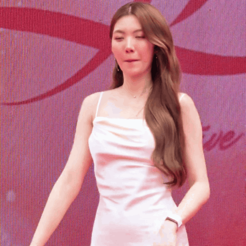 A Woman In A White Dress Is Standing In Front Of A Large Screen With The Word Love On It GIF