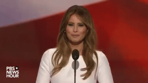A Woman In A White Dress Is Standing In Front Of A Microphone On A Stage . GIF