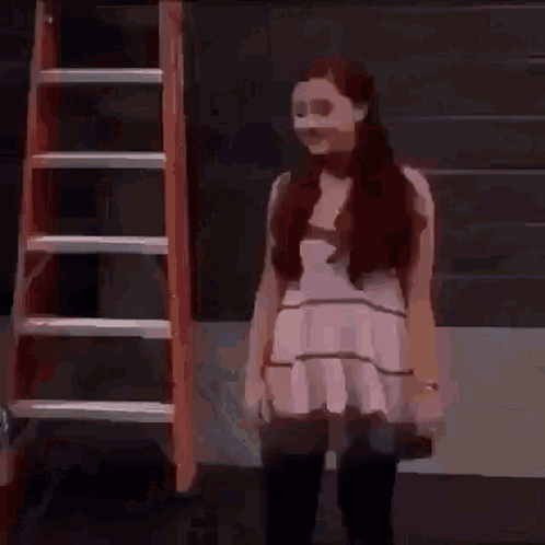 A Woman In A White Dress Is Standing In Front Of A Red Ladder . GIF