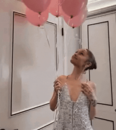A Woman In A White Dress Is Standing In Front Of A White Wall GIF