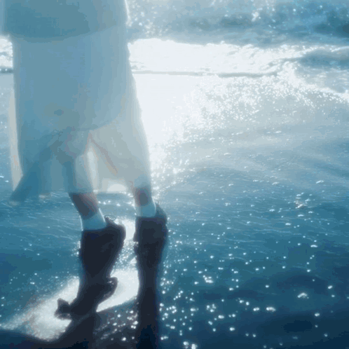 A Woman In A White Dress Is Standing In The Ocean GIF