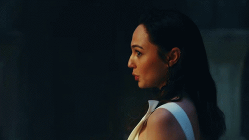 A Woman In A White Dress Is Standing Next To A Man In A Dark Room . GIF