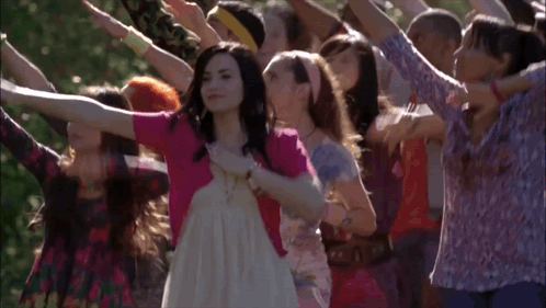 A Woman In A White Dress Is Surrounded By Other Women GIF
