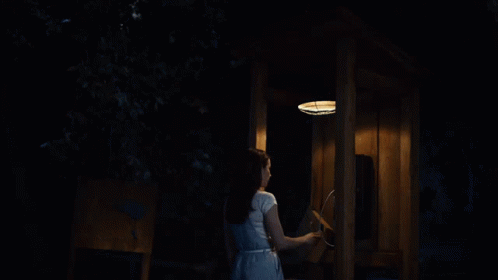 A Woman In A White Dress Is Talking On A Phone GIF