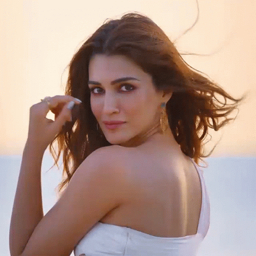 A Woman In A White Dress Looks Over Her Shoulder GIF