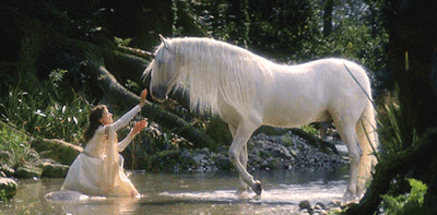 A Woman In A White Dress Reaches Out To A White Horse In A Stream GIF