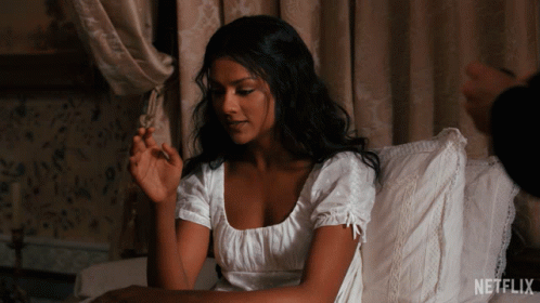 A Woman In A White Dress Sits On A Bed With A Netflix Logo On The Bottom GIF