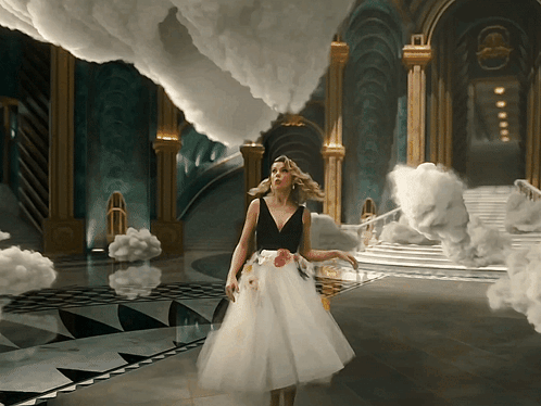 A Woman In A White Dress Stands In A Room With Clouds GIF