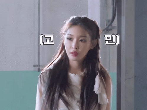 A Woman In A White Dress Stands In Front Of A Wall With Chinese Writing On It GIF