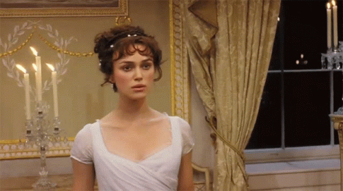 A Woman In A White Dress Stands In Front Of Candles GIF