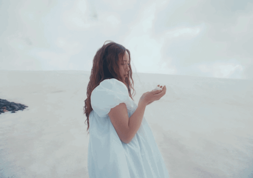 A Woman In A White Dress Stands On A Beach GIF