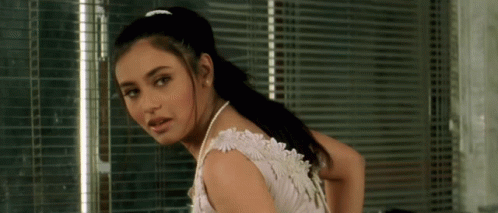 A Woman In A White Dress With Pearls Around Her Neck GIF