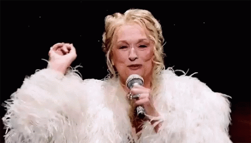 A Woman In A White Fur Coat Is Holding A Microphone . GIF