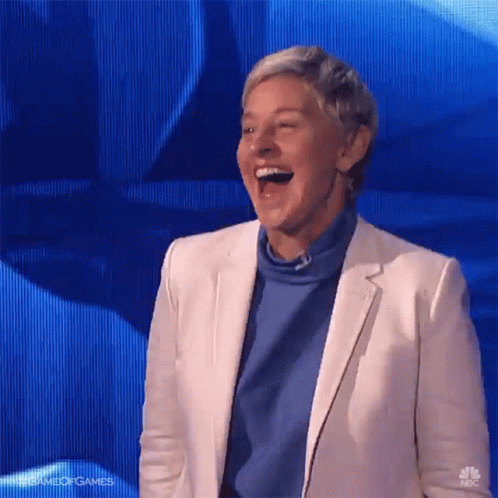 A Woman In A White Jacket And Blue Sweater Is Laughing GIF