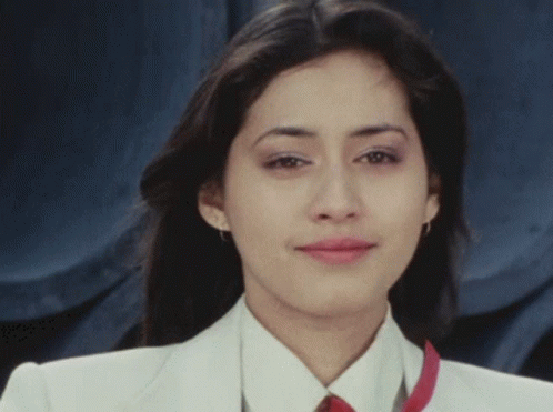 A Woman In A White Jacket And Red Tie Is Smiling GIF