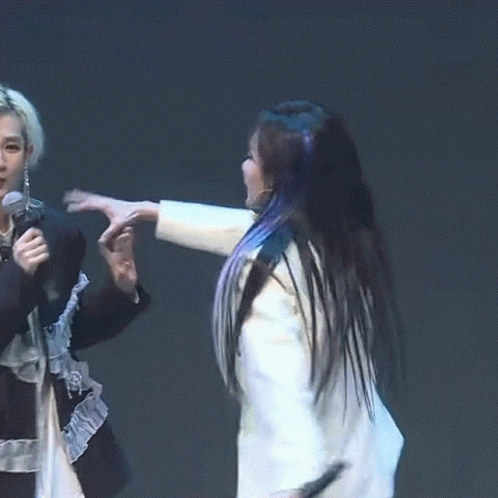 A Woman In A White Jacket Holds A Microphone While A Woman In A Black Shirt Holds A Microphone In Her Hand GIF