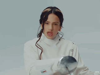 A Woman In A White Jacket Is Holding A Silver Ball In Her Hand GIF
