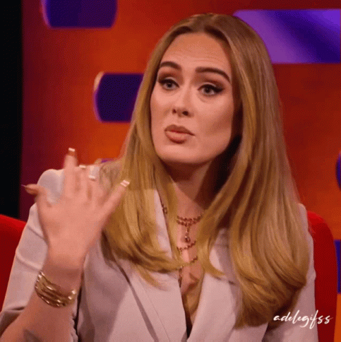 A Woman In A White Jacket Is Sitting In A Red Chair With Adultgifs Written On The Bottom Right Corner GIF