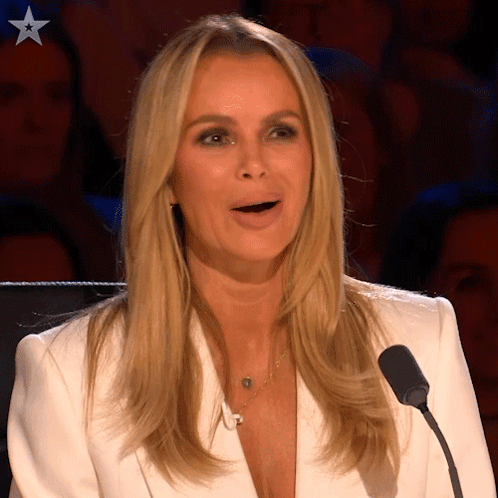A Woman In A White Jacket Is Speaking Into A Microphone With A Star On Her Chest GIF