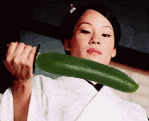 A Woman In A White Kimono Is Holding A Green Cucumber In Her Hands GIF