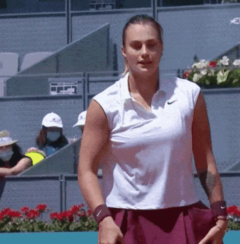 a woman in a white nike shirt is holding a tennis racquet on a tennis court