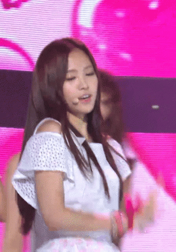 A Woman In A White Off The Shoulder Top Is Dancing On A Stage GIF