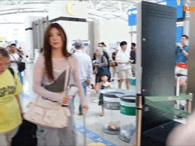 Woman With White Purse Walking Through Airport GIF