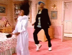 A Woman In A White Robe Is Dancing With A Man In A Black Jacket GIF