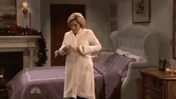 a woman in a white robe is standing in a bedroom next to a bed .