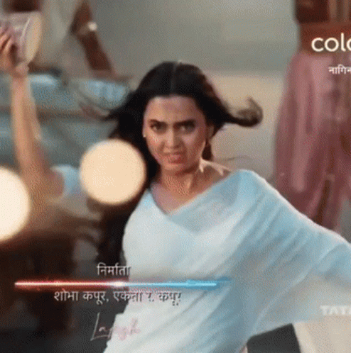 A Woman In A White Saree Is Dancing In Front Of A Sign That Says Color GIF