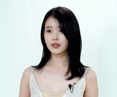 A Woman In A White Sequined Dress Has A Microphone On Her Chest GIF