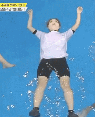 A Woman In A White Shirt And Black Shorts Is Floating In A Swimming Pool . GIF