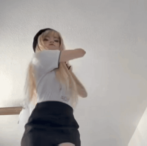 A Woman In A White Shirt And Black Skirt Is Standing In A Room . GIF