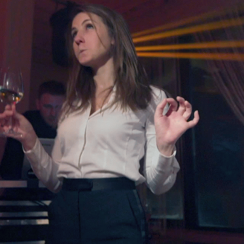 A Woman In A White Shirt Holds A Glass Of Wine In Front Of A Yamaha Keyboard GIF