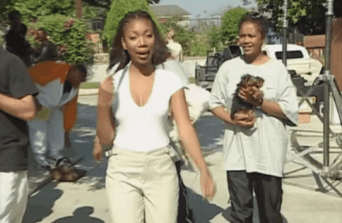 A Woman In A White Shirt Holds A Small Dog In Her Hands GIF