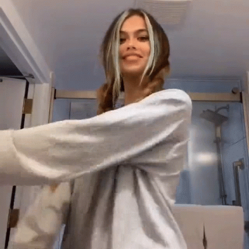 A Woman In A White Shirt Is Dancing In A Bathroom . GIF